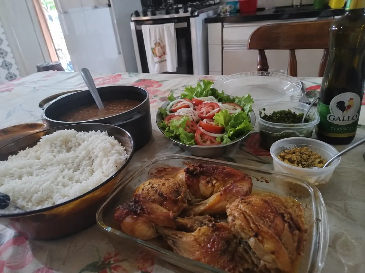 Almoço servido: arroz, feijão, frango assado e salada na mesa da cozinha